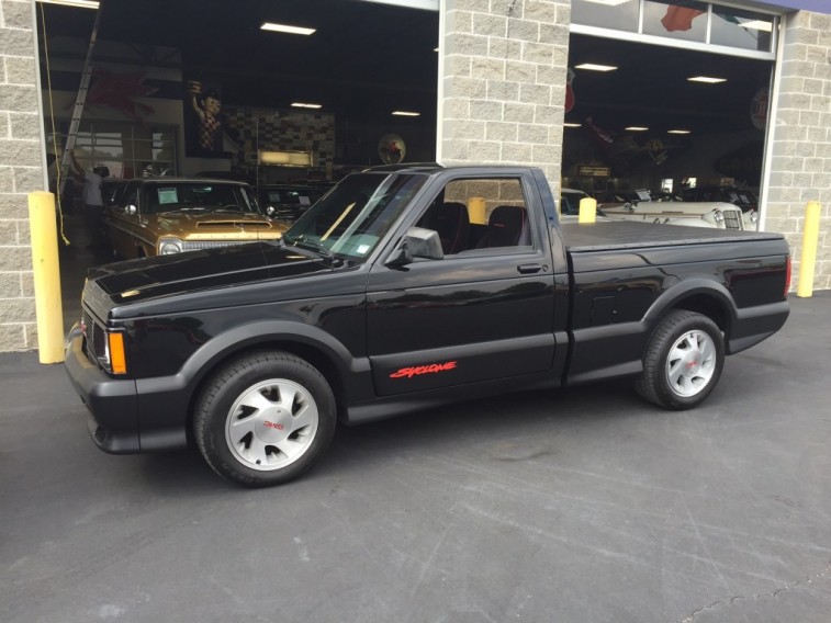 A 1991 GMC Syclone parked in front of an auto garage 