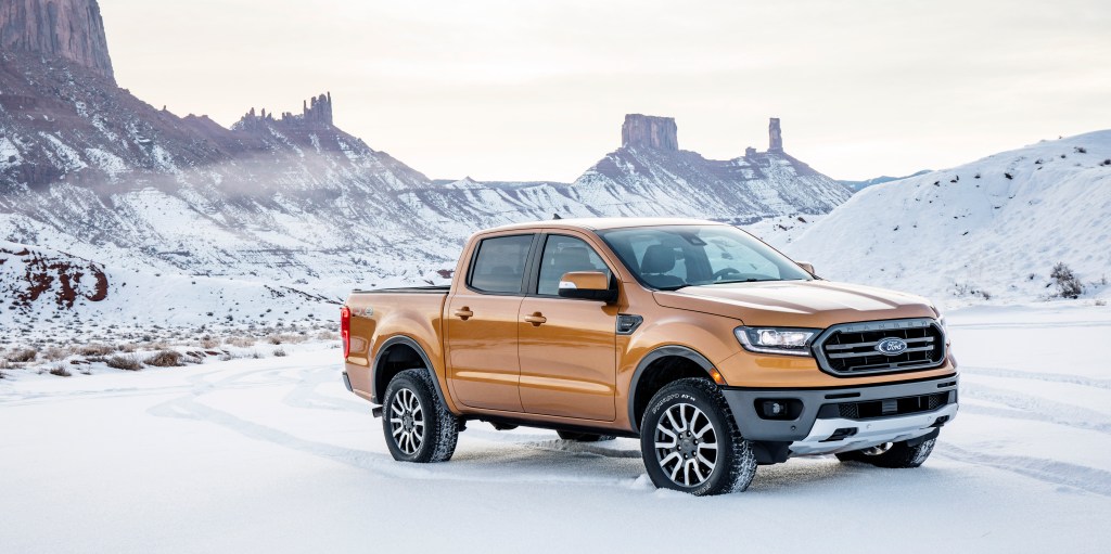 An orange crew cab 2019 Ford Ranger is parked in front of snow-covered mountains