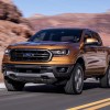 An orange 2019 Ford Ranger at speed on a road with a mountain background
