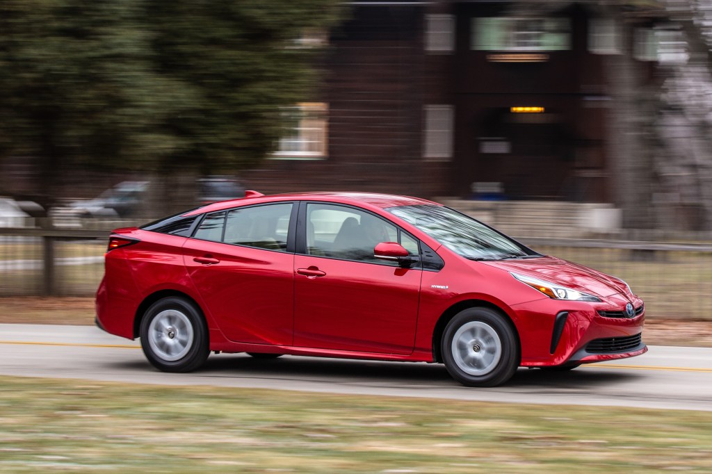 a red toyota prius drives down the road