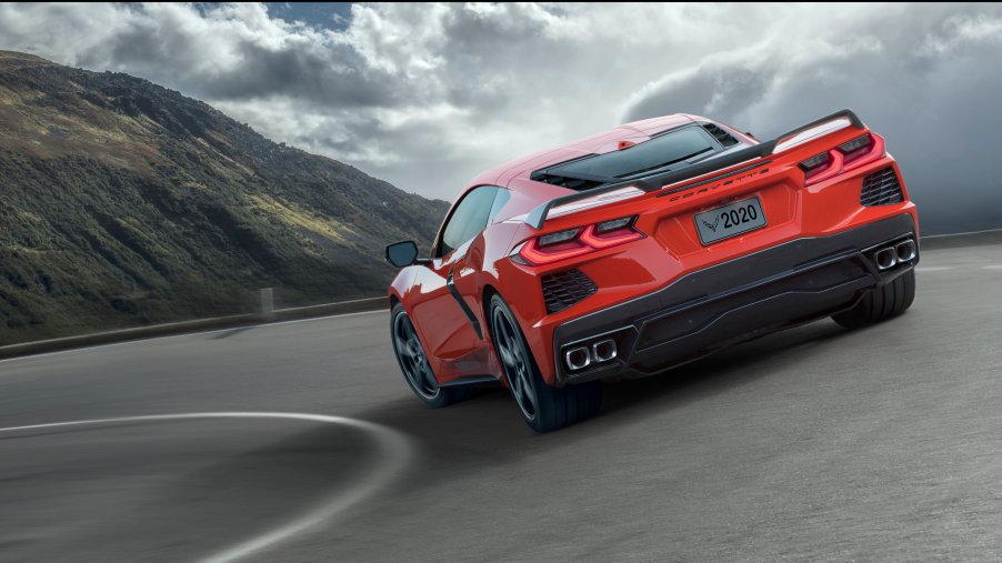 A red Corvette rounds a turn on a mountain pass.
