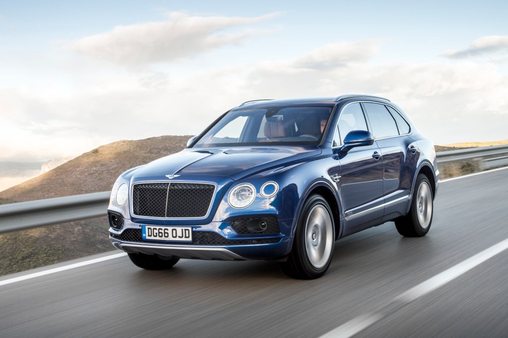 a blue Bentley Bentayga luxury SUV at speed on a scenic road