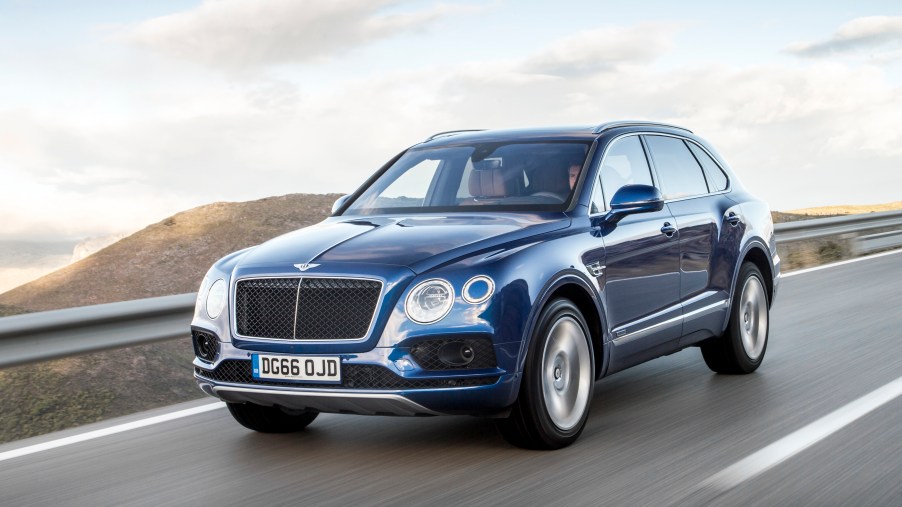 a blue Bentley Bentayga SUV at speed on a scenic road