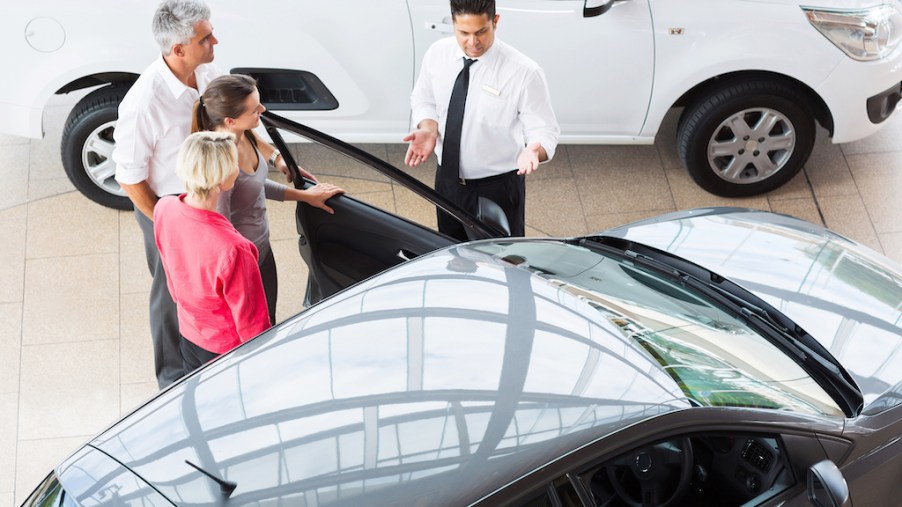 View of car salesman showing vehicle to family