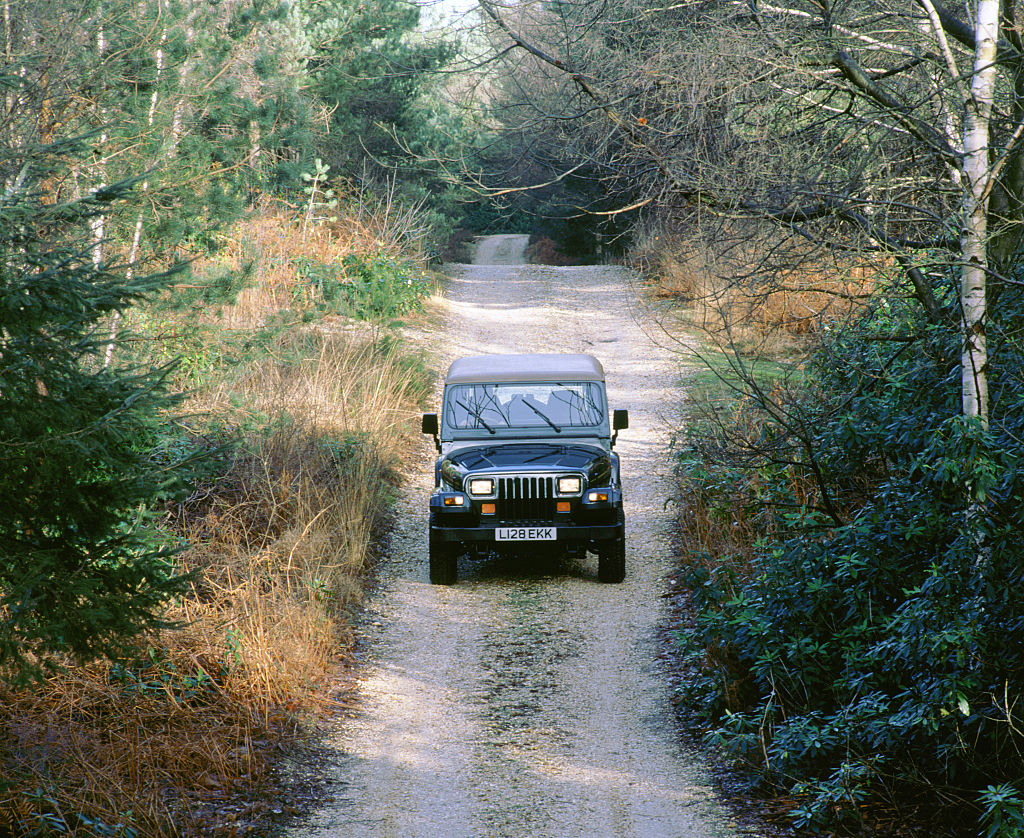 Jeep Wrangler driving down a dirt road.