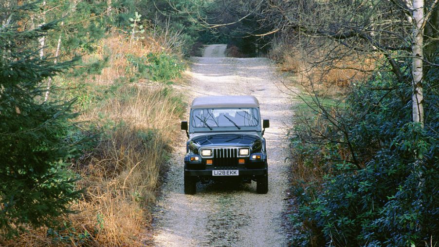 Jeep Wrangler driving down a dirt road.