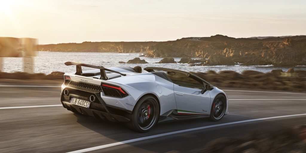A white Lamborghini Huracan Preformante Spyder driving down a coastal road