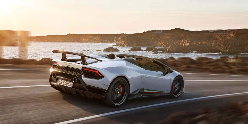 A white Lamborghini Huracan Preformante Spyder driving down a coastal road