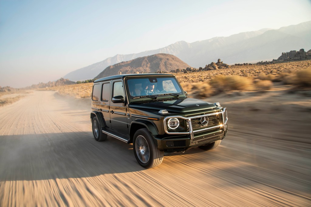 A black G-Wagon driving fast in the sand, making use of its twin-turbo V8