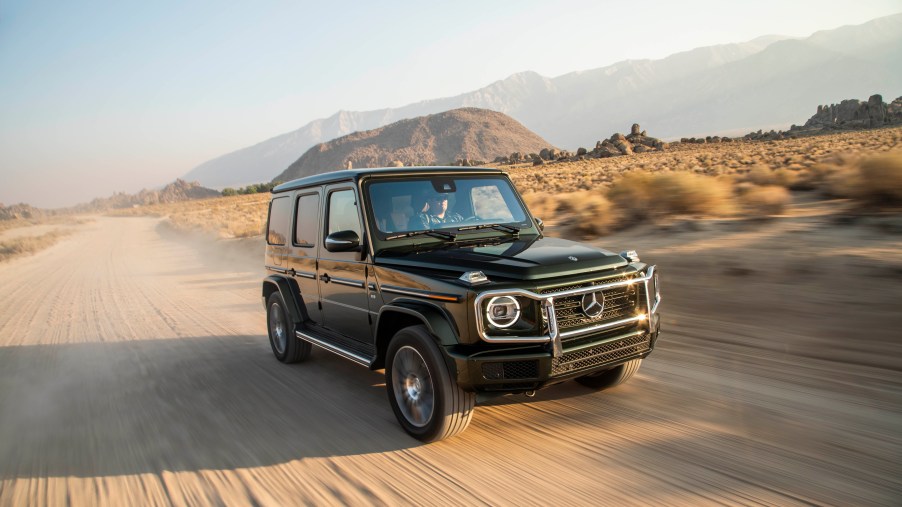 A black G-Wagon driving fast in the sand