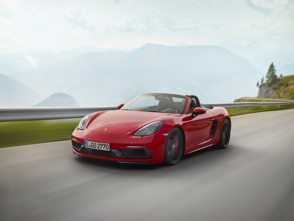 A red Porsche 718 Boxster driving down a beautiful mountain road.