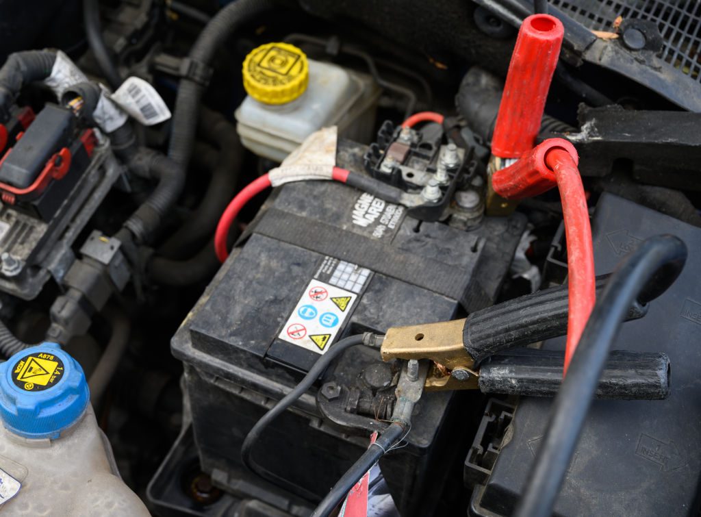 Red and black jumper cables attached to car battery terminals