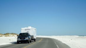 GMC pick-up truck towing a camper trailer down a Pensacola highway