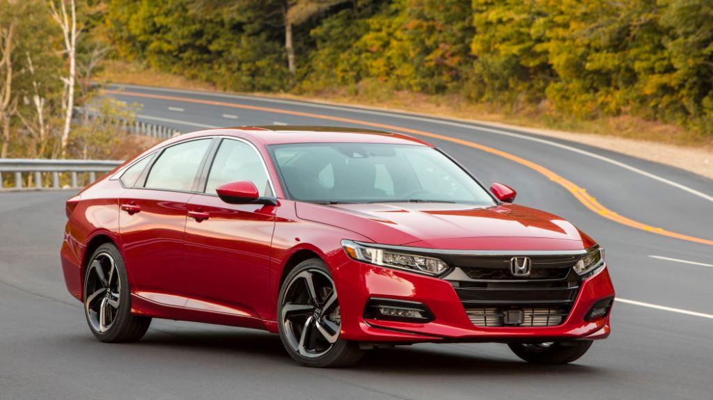 A red 2018 Honda Accord sedan on a winding scenic road. This platform is popular with those car shopping.