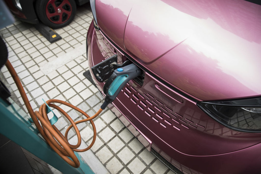A Baojun E100 electric vehicle stands plugged in to a charging station