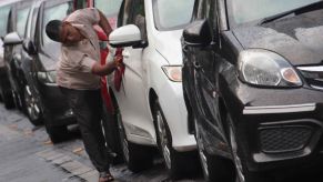 A man detailing his car. Wiping it down with a towel.