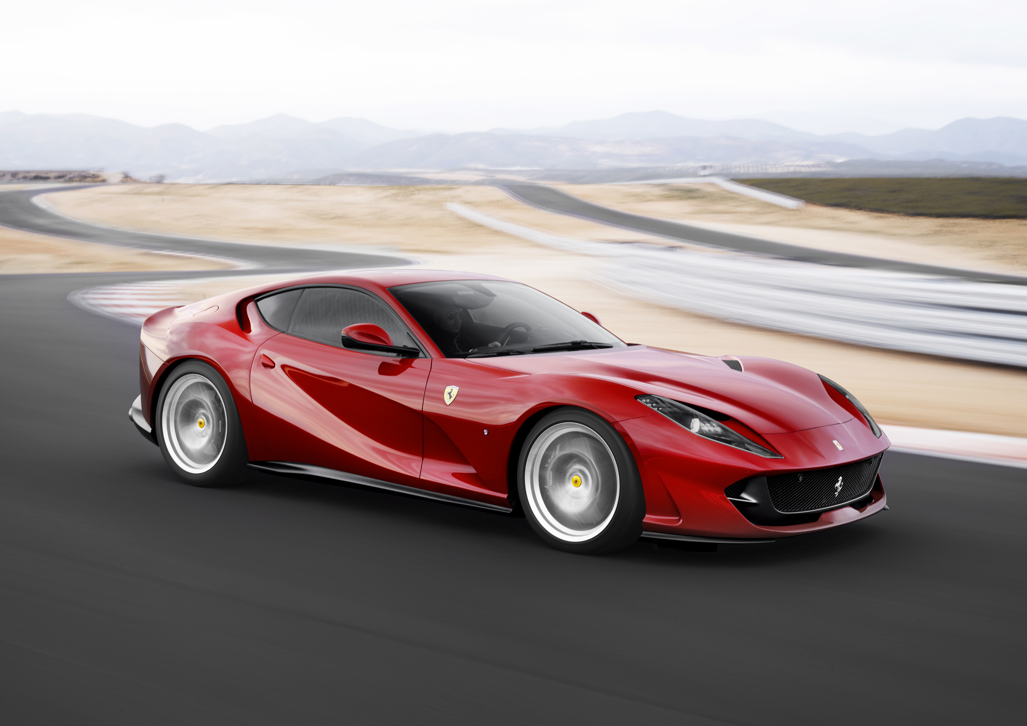 A red Ferrari 812 Superfast taking a turn at a racetrack