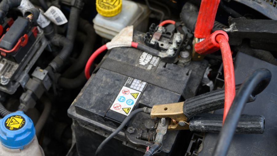 A pair of roadside emergency kit jumper cables are attached to battery terminals.