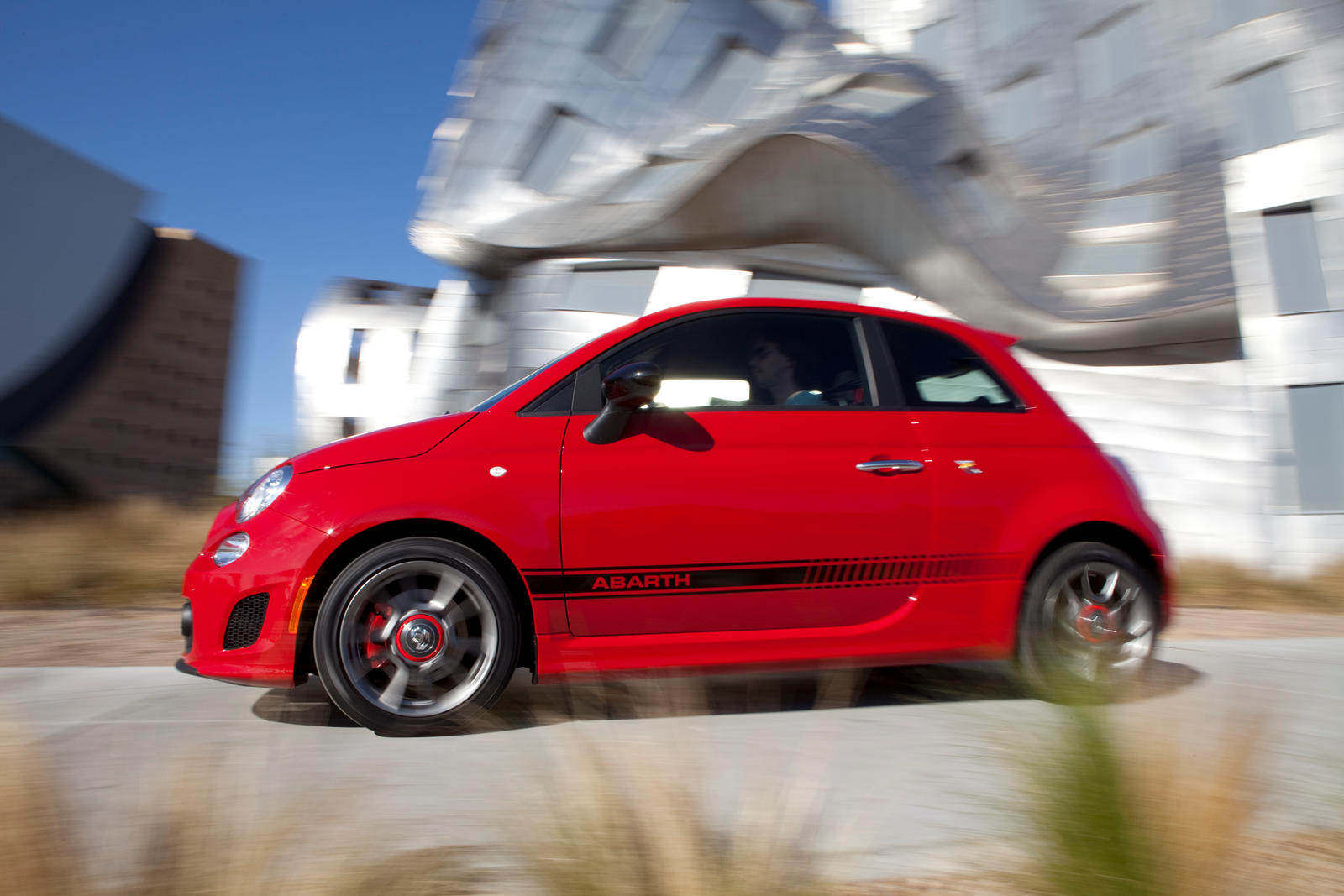 A red FIAT 500 Abarth zips around a curve.
