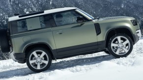 A 2020 Land Rover Defender, two-door model, ascends a hill in the snow.