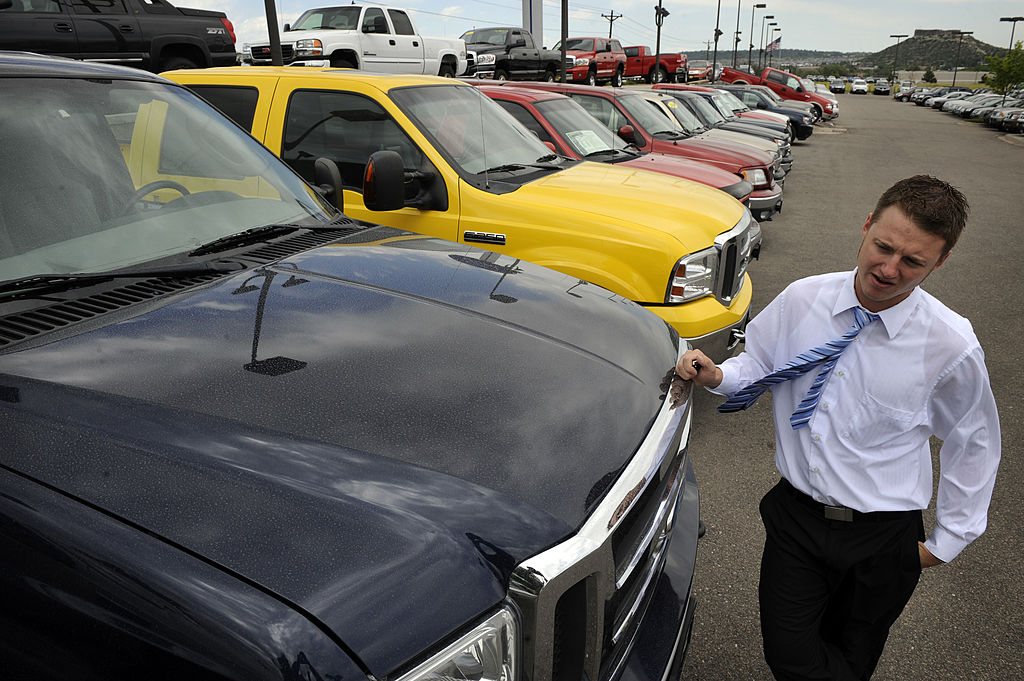 Car salesman leans against a 2005 Ford Supercab F-350 diesel truck
