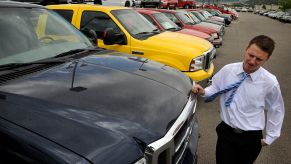 Car salesman leans against a 2005 Ford Supercab F-350 diesel truck