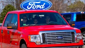 A red 2012 Ford F-150 driving off the car lot.