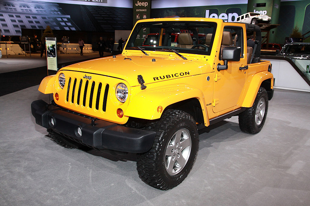 A yellow 2012 Jeep Wrangler on display at an auto show.