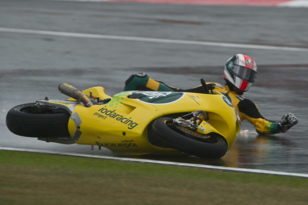 A motorcycle racer skidding on the pavement after crashing his bike.