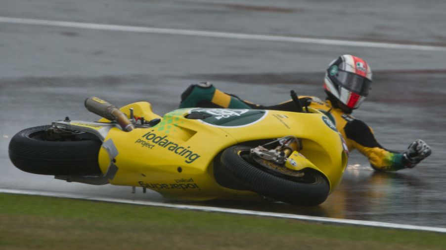A motorcycle racer skidding on the pavement after crashing his bike.