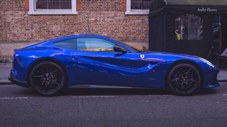 A blue Ferrari F12 Berlinetta parked on the street.