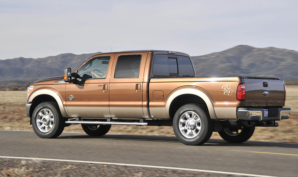 A brown Ford F-250 driving down the highway.