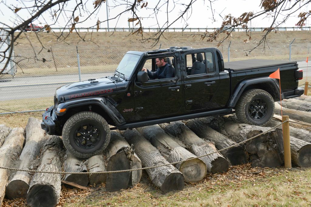A Jeep Gladiator being test driven over a pile of logs.