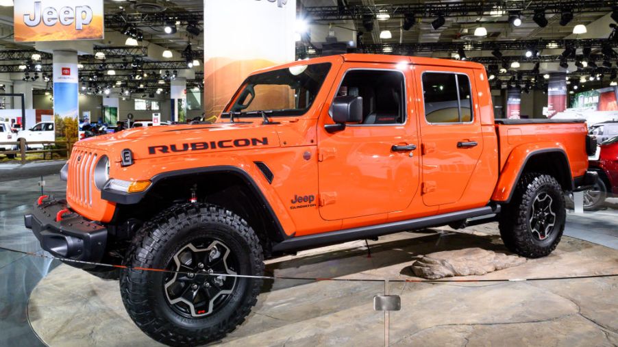 An orange Jeep Gladiator on display at an auto show.