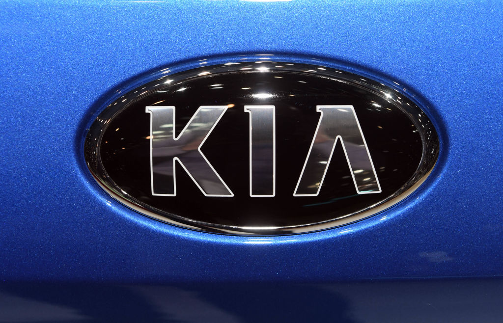 Kia's emblem on the front of a blue vehicle.