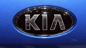 Kia's emblem on the front of a blue vehicle.