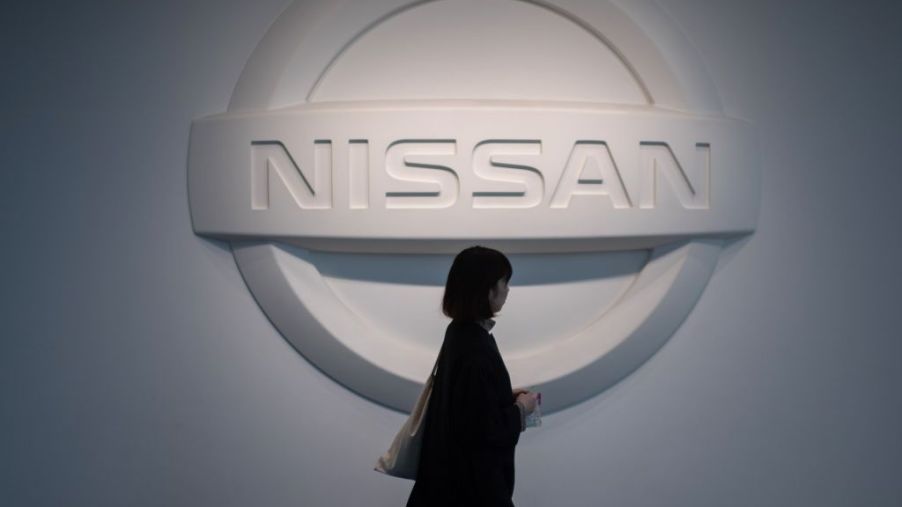 Woman walking by a big Nissan logo on the wall.