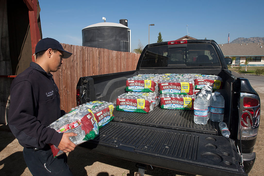 A person loading crates of bottled water into the bed of a pickup truck.