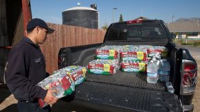 A person loading crates of bottled water into the bed of a pickup truck.