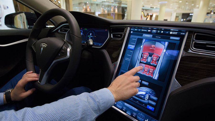 Man sitting in a Tesla using the infotainment screen.