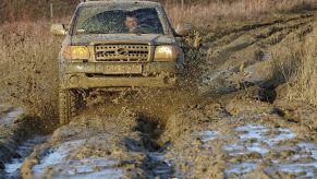 A truck off-roading through a big puddle of mud.