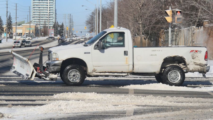 A white pickup truck with a snowplow attached.