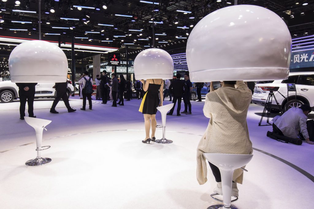 Attendees sit and stand under virtual reality domes at the Auto Shanghai 2019 show