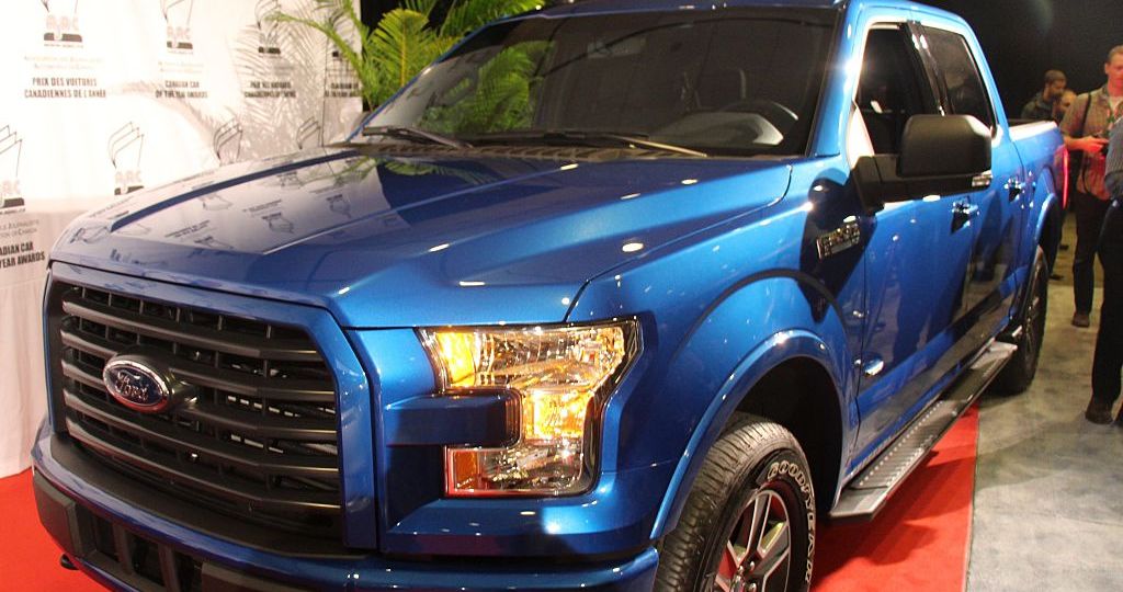 A blue 2015 Ford F-150 on display at an auto show.