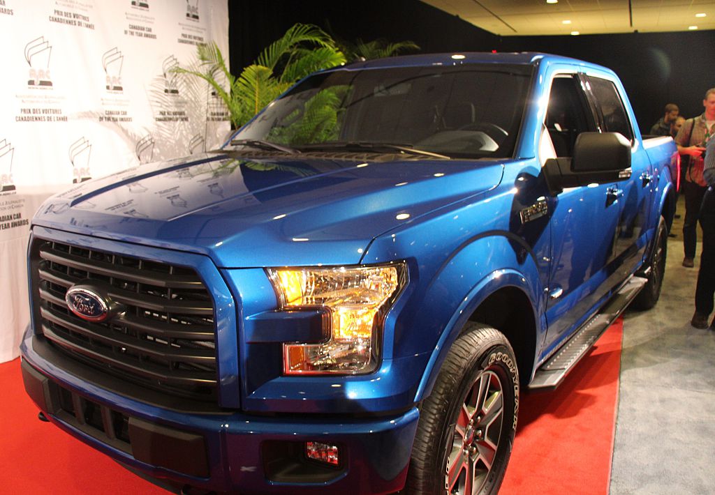 A blue 2015 Ford F-150 on display at an auto show.