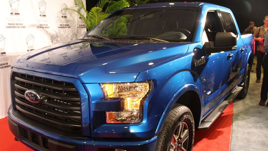 A blue 2015 Ford F-150 on display at an auto show.