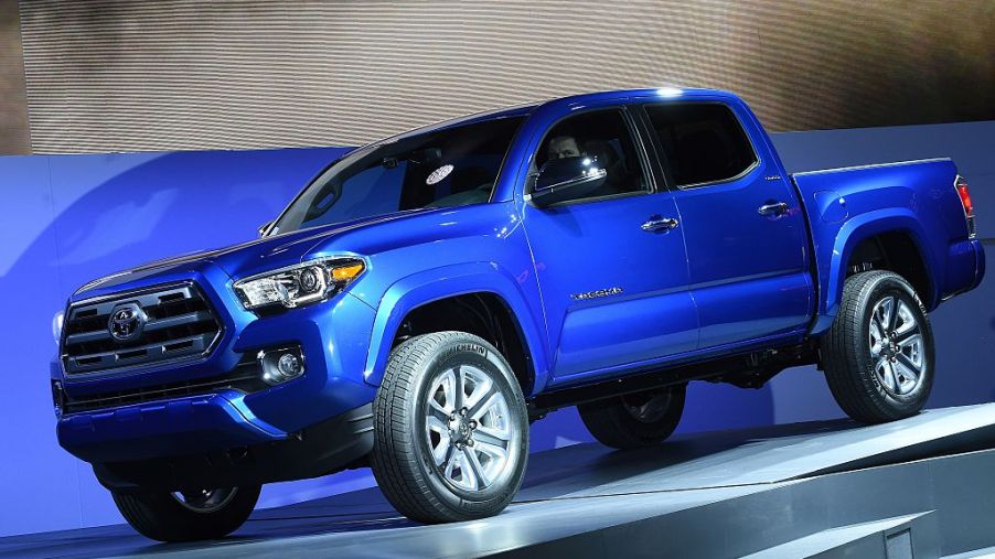 A blue Toyota Tacoma being unveiled at an auto show.