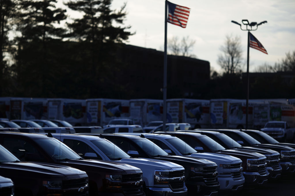 American flags fly near GM Chevrolet pickup trucks displayed for sale at a car dealership