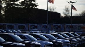 American flags fly near GM Chevrolet pickup trucks displayed for sale at a car dealership
