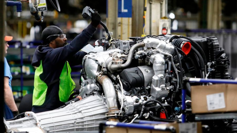 Workers help assemble an engine at a GM plant.